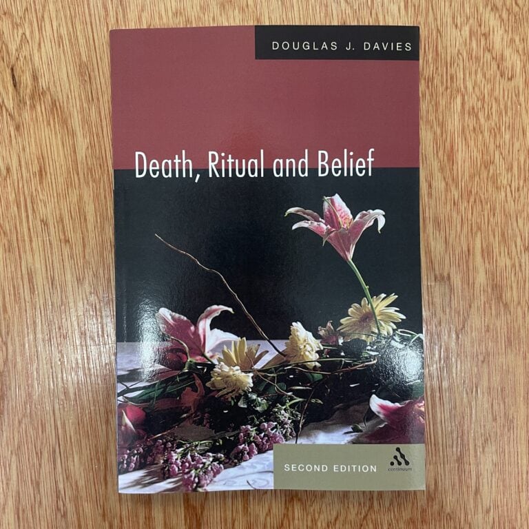 Book titled 'Death, Ritual and Belief' by Douglas J. Davies, second edition, with floral cover design, on a wooden surface.